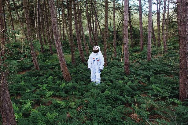 Astronaut steht in einem Wald