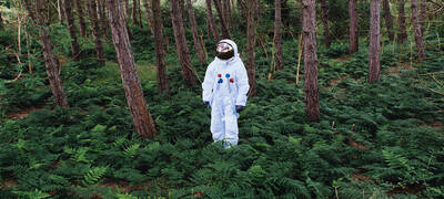 Eine als Astronaut verkleidete Person steht im Wald