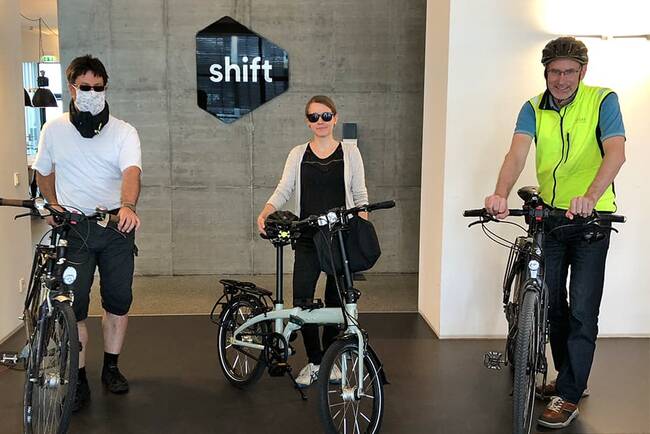 Zwei Kollegen (Links, rechts) und eine Kollegin (Mitte) mit ihren Fahrrädern im Shift Büro